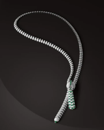 Elegant necklace with white and green gemstones, set against a dark background, highlighting its intricate design and luxurious appearance.