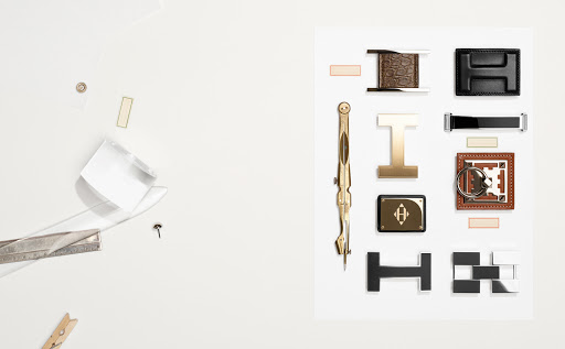 Arrangement of hardware pieces on white background, including metal compass, buckle pieces, and geometric shapes in symmetrical arrangement.
