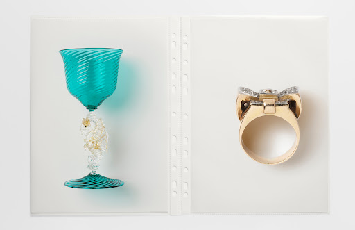 Elegant display showcasing a blue Murano glass goblet and a gold ring with diamonds, photographed in a well-lit studio setting.