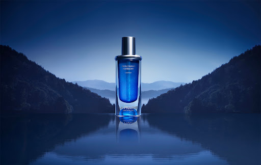 La Prairie Skin Caviar Harmony L'Extrait bottle on reflective surface with mountain backdrop in shades of blue and silver tones.