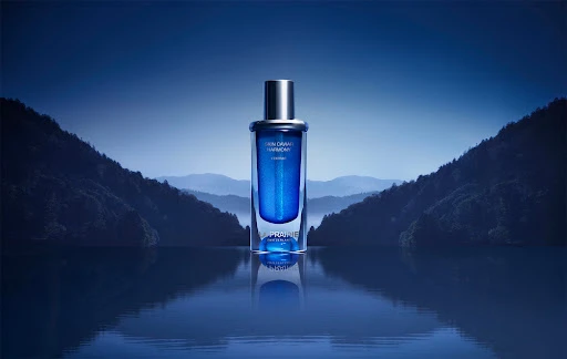 La Prairie Skin Caviar Harmony L'Extrait bottle on reflective surface with mountain backdrop in shades of blue and silver tones.