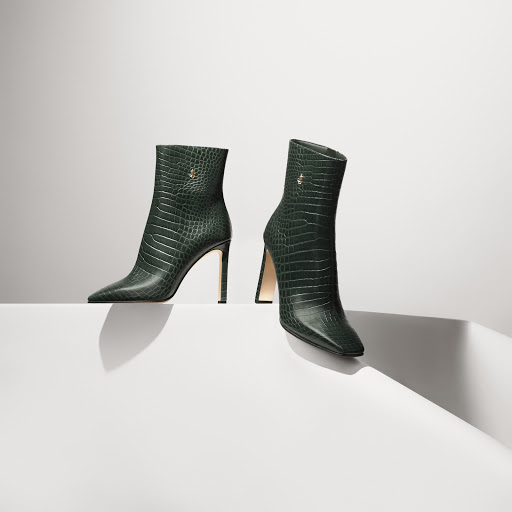 Two elegant green ankle boots with a textured finish are displayed on a clean white surface against a soft, gradient background.