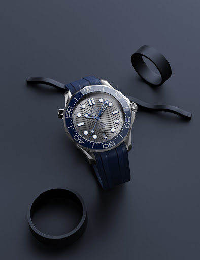 Elegant wristwatch with blue rubber strap and silver casing on a dark blue background, complemented by black decorative rings.