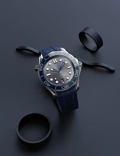 Elegant wristwatch with blue rubber strap and silver casing on a dark blue background, complemented by black decorative rings.