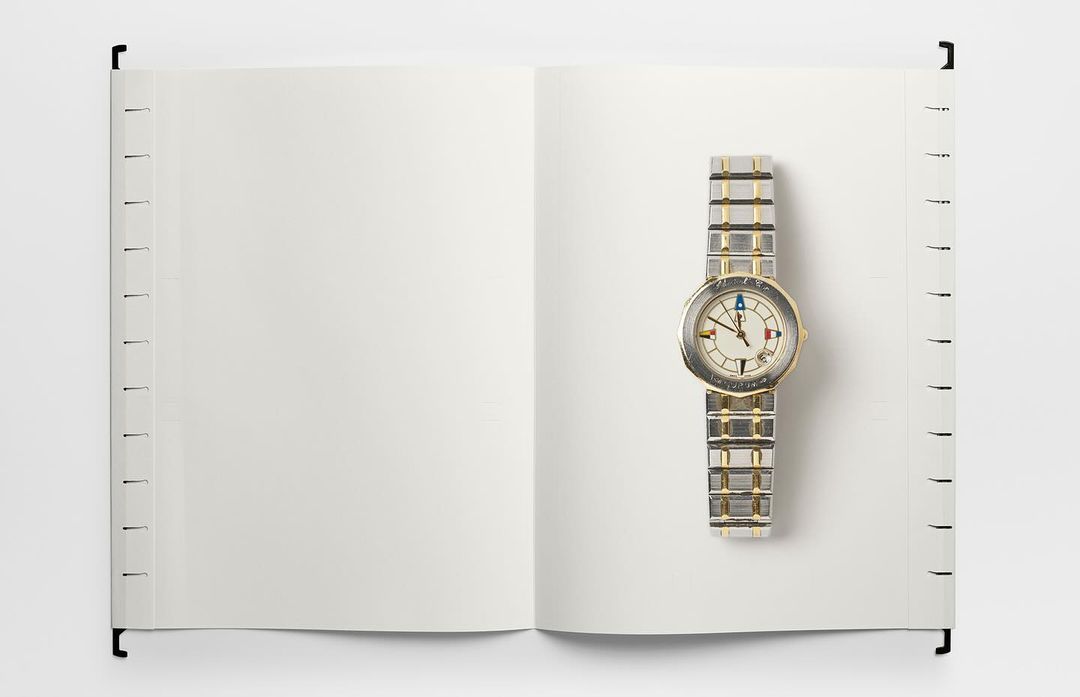 Open notebook with blank pages and a stylish silver wristwatch. The watch is on the right page, emphasizing time and space.