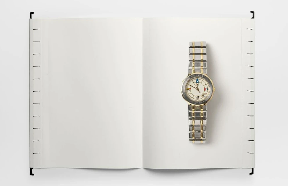 Open notebook with blank pages and a stylish silver wristwatch. The watch is on the right page, emphasizing time and space.