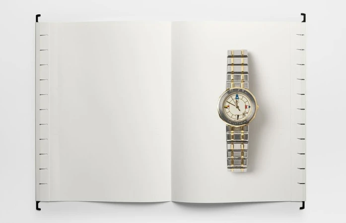 Open notebook with blank pages and a stylish silver wristwatch. The watch is on the right page, emphasizing time and space.