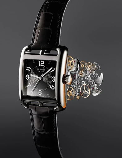 Elegant Hermès watch with black leather strap, silver case, black dial, and visible watch mechanism on a seamless dark gradient background.