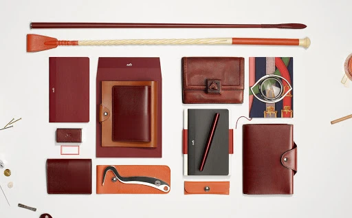 Arrangement of maroon and brown leather accessories and riding crop on a white background, suitable for fashion or lifestyle promotion.