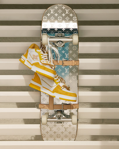 Elevated view of a skateboard with Louis Vuitton monogram design and yellow and white high-top sneakers stacked on top of it.