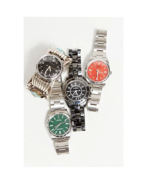 Overhead studio shot of five wristwatches with stainless steel and ceramic bands against a white backdrop. One has a turquoise bracelet.