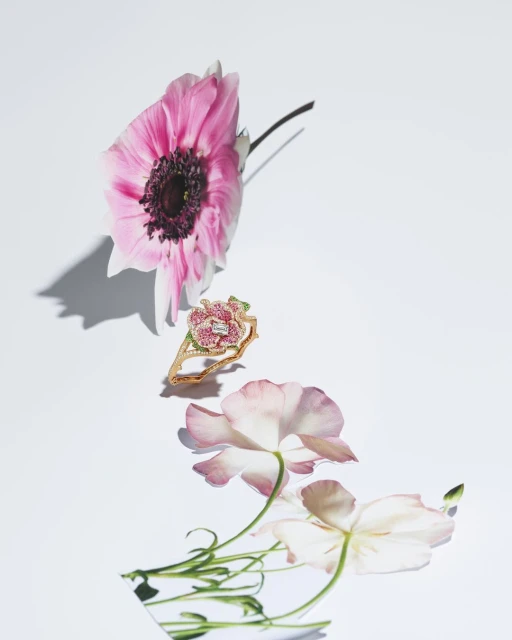 Floral-themed jewellery shot featuring a ring with a floral design, pink petals, and a white background under bright studio lighting.