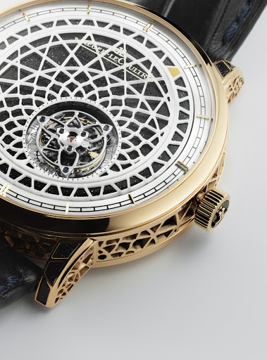 Elegant gold wristwatch with intricate white and black patterned face and dark leather band, close-up view of the timepiece.