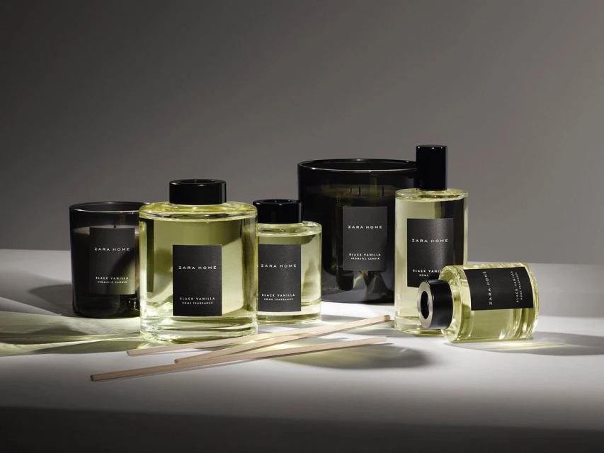 Zara Home fragrance collection featuring candles, reed diffusers, and sprays in glass containers with minimalist black labels and wooden sticks.