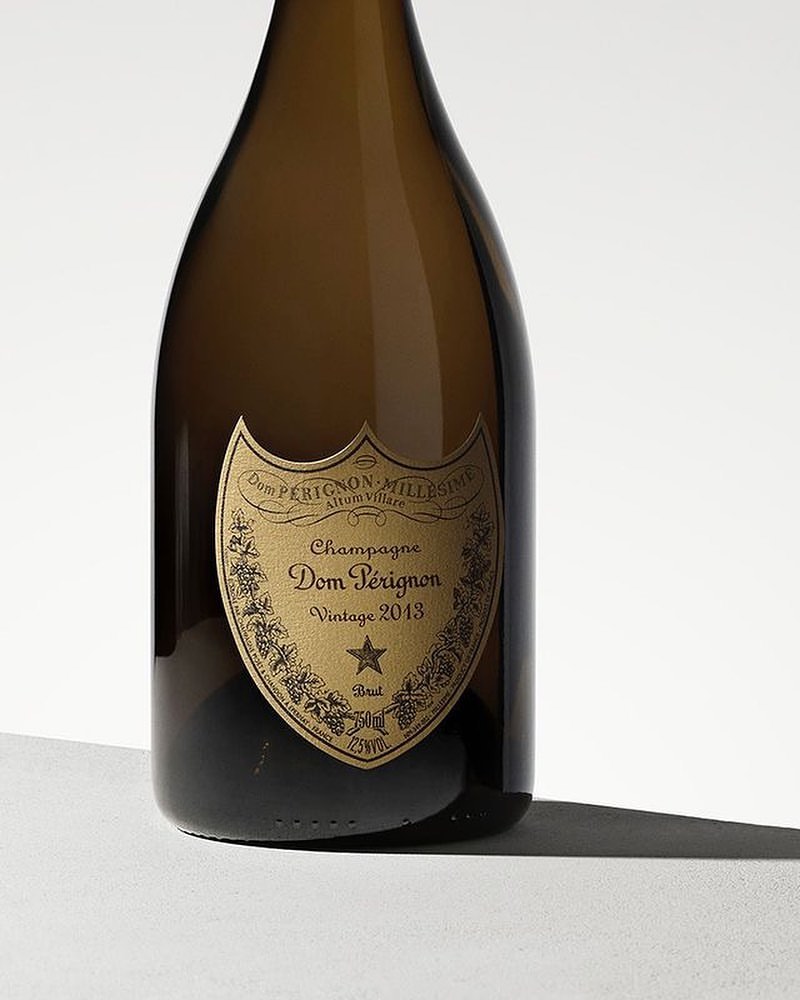 Dom Pérignon champagne bottle, Vintage 2013, studio shot. The bottle has a gold label and is set against a neutral background.