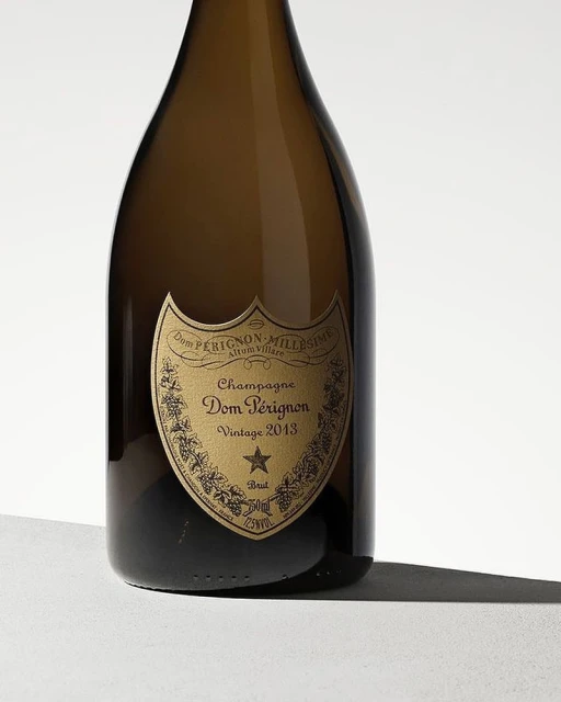 Dom Pérignon champagne bottle, Vintage 2013, studio shot. The bottle has a gold label and is set against a neutral background.