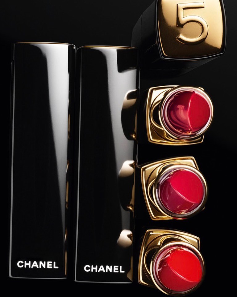 Elevated shot of Chanel No. 5 lipstick collection featuring glossy black and gold tubes, emphasizing luxury beauty and product presentation.