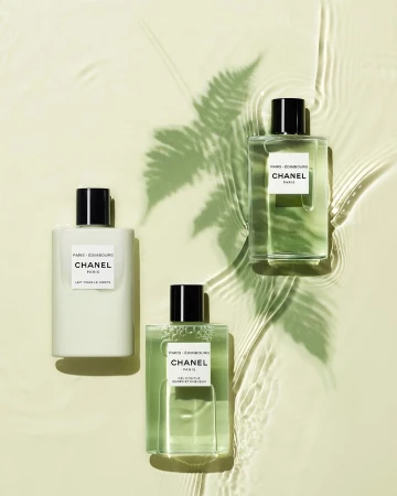 Three Chanel Paris Les Eaux De Chanel bottles are arranged on a light background with a fern shadow and water ripple effect.