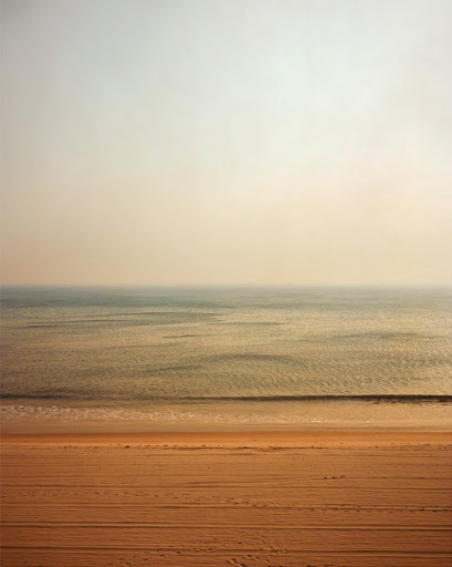 Beach scene with sand and water in a calming, minimalist composition with muted colors, creating a serene and tranquil landscape.