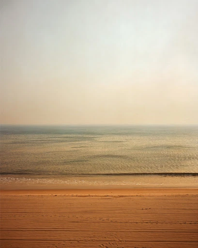 Beach scene with sand and water in a calming, minimalist composition with muted colors, creating a serene and tranquil landscape.