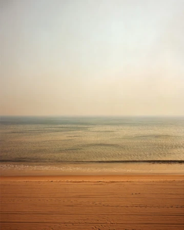 Beach scene with sand and water in a calming, minimalist composition with muted colors, creating a serene and tranquil landscape.