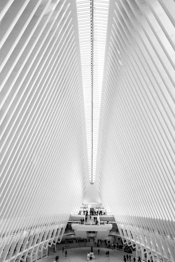 Black and white architectural shot of the Oculus in New York City with the building's soaring ribbed white design and people in the interior.