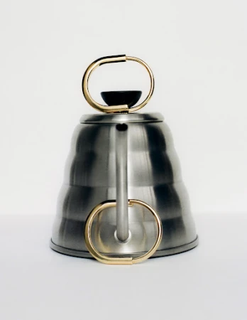 Elevated shot of a silver-colored tea kettle with gold handle, minimalist design against a white background, product photography.