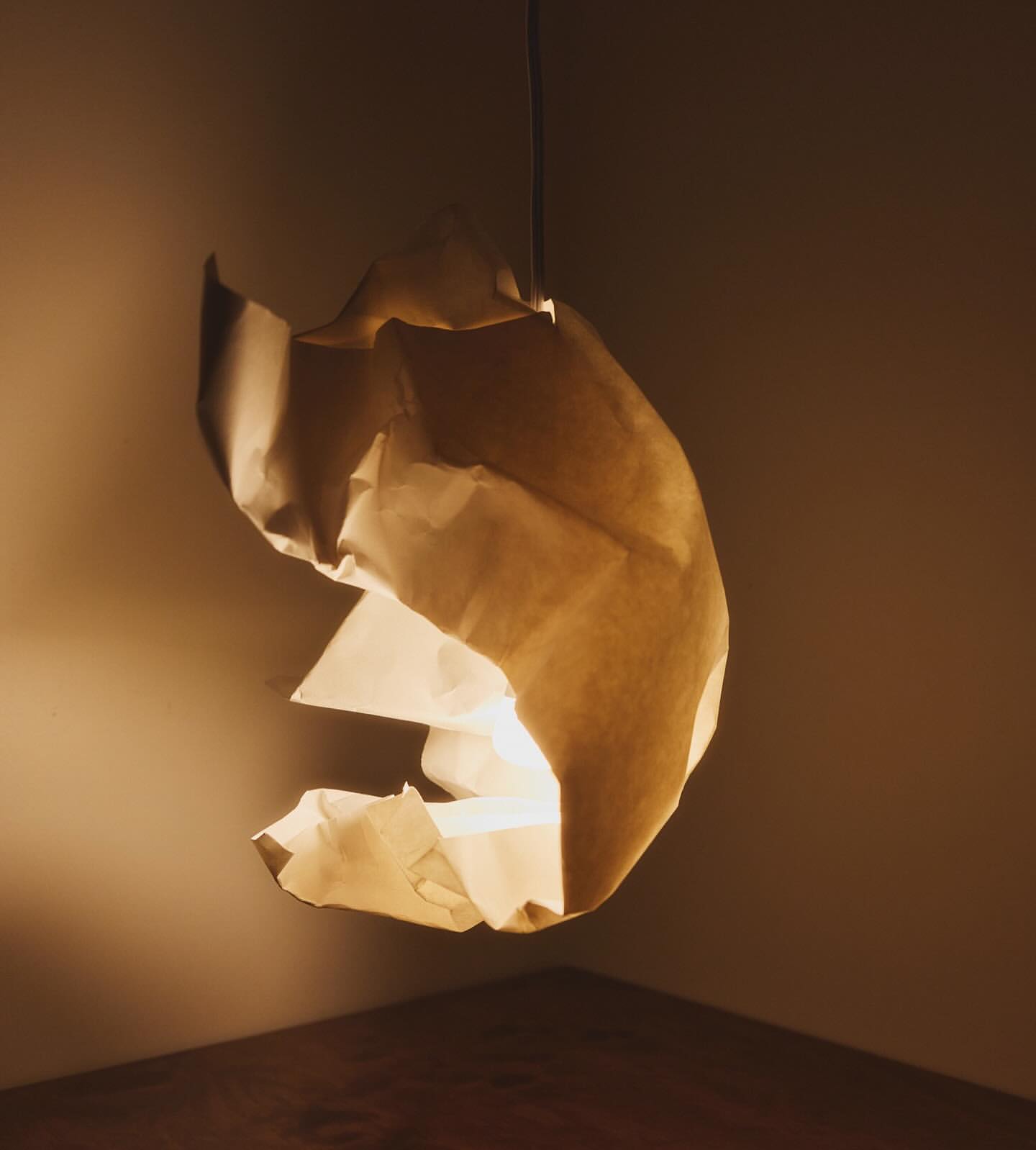 Indoor view of a paper pendant light fixture that has a modern design, hanging from the ceiling and casting a warm glow in the room.