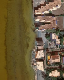 Overhead aerial photograph of a coastal area featuring buildings and murky water along the shoreline by photographer Sam Kweskin.