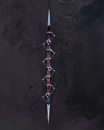 Overhead aerial view of an eight person rowing shell gliding on dark water captured by photographer Sam Kweskin.