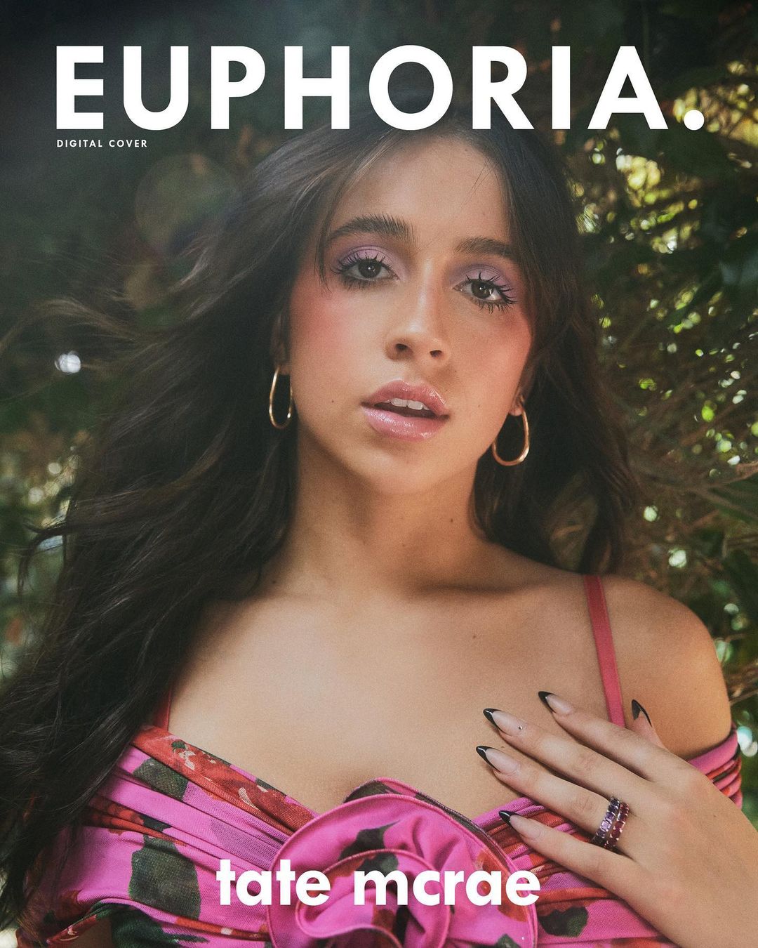 Close-up of Tate McRae on Euphoria digital cover, wearing a pink floral top with gold hoop earrings, against a green leafy backdrop.