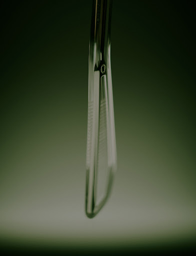 Extreme close-up of a sleek metallic tool handle with textured grip captured against a dark moody green gradient background.