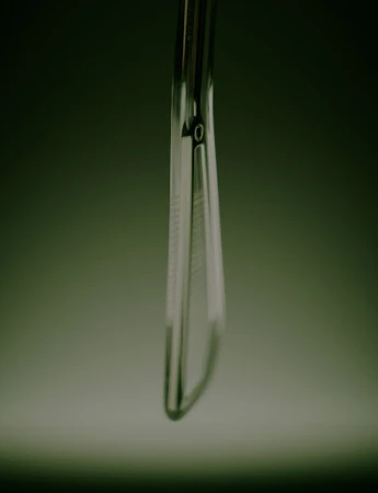 Extreme close-up of a sleek metallic tool handle with textured grip captured against a dark moody green gradient background.