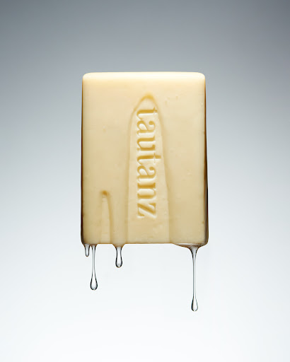 Close-up of a rectangular bar of soap with the word 'lautanz' vertically embossed, set against a smooth, graduated grey background.