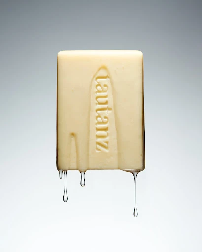 Close-up of a rectangular bar of soap with the word 'lautanz' vertically embossed, set against a smooth, graduated grey background.