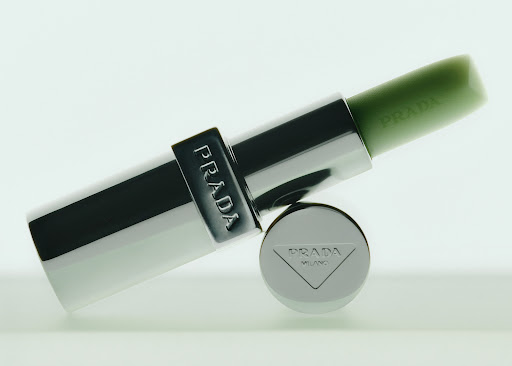 Prada lipstick in silver tube and green color on a white background. Beauty and fashion product shot with studio lighting.  