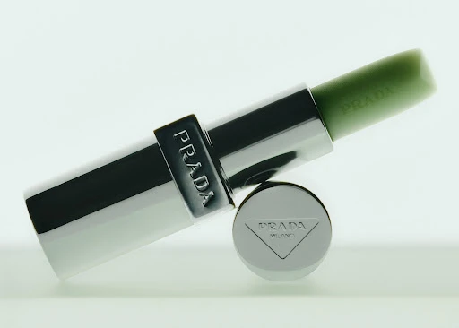 Prada lipstick in silver tube and green color on a white background. Beauty and fashion product shot with studio lighting.  