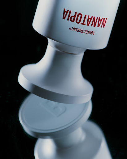 Close-up studio shot of a glossy white bottle with red sans-serif text on a reflective black surface, emphasizing product design.