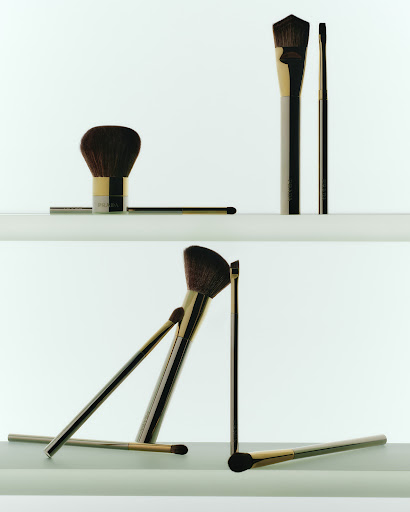 Makeup brushes on a shelf against a white background in an eye-level shot. Cosmetic brushes, including a blush brush, are displayed.