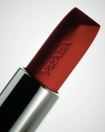 Macro shot of a red Prada lipstick with textured surface in a silver case against a white background