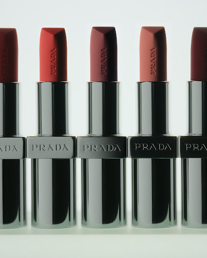 Five Prada lipsticks in silver metallic cases arranged in a neat row against a bright white background.