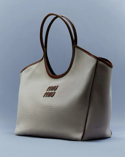Beige Miu Miu handbag with brown trim and handles on a light blue background, showcasing fashion accessory, style, and craftsmanship.