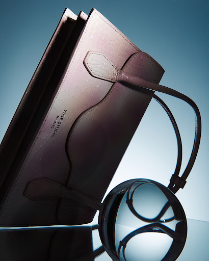 Close-up studio shot of a pink leather-bound folio with a clear crystal ball creating optical distortions and reflections on a glossy surface.
