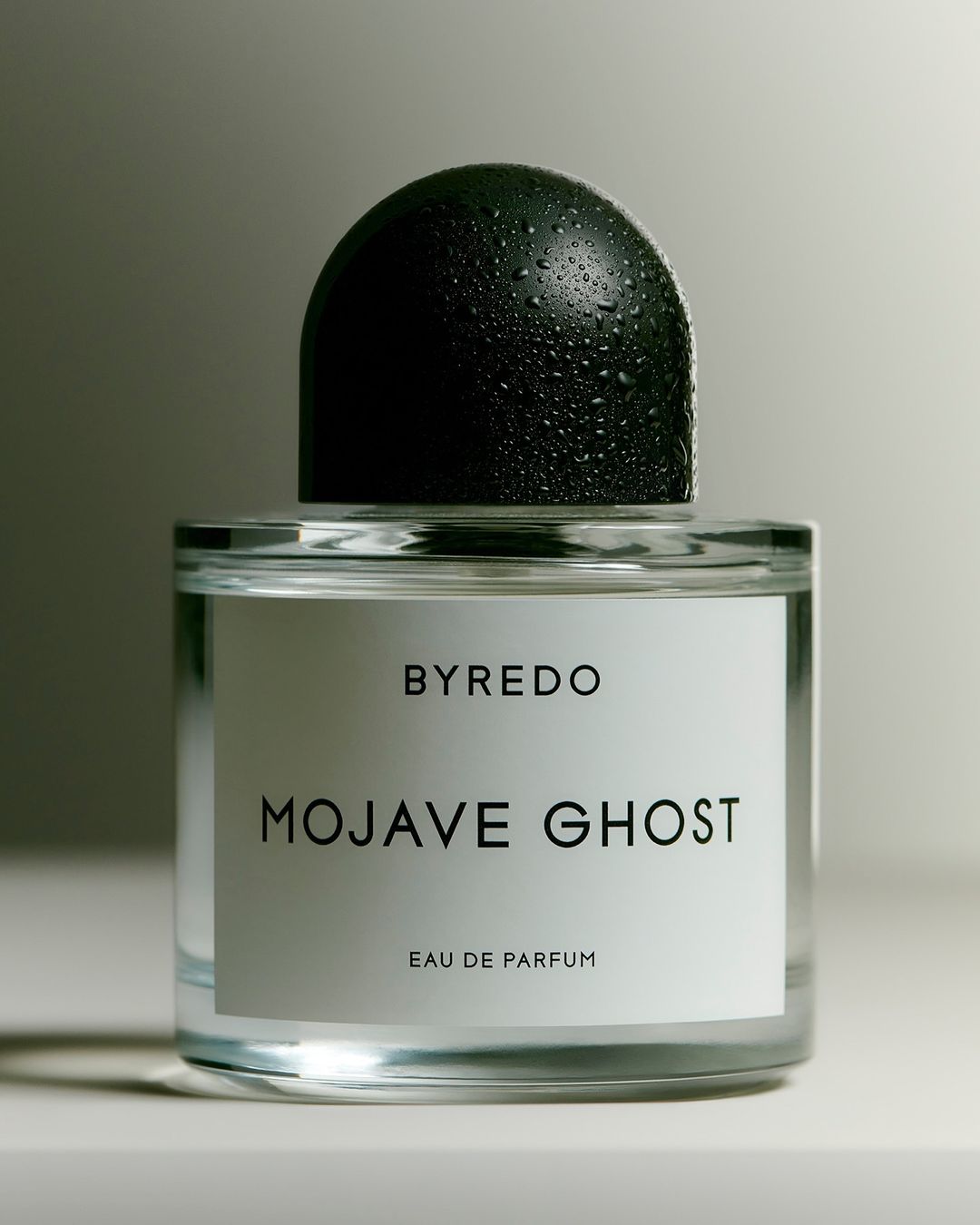 Byredo Mojave Ghost Eau de Parfum bottle with a clear glass container, black cap covered with water droplets, and white label.