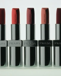 Five Prada lipsticks in silver metallic cases arranged in a neat row against a bright white background.