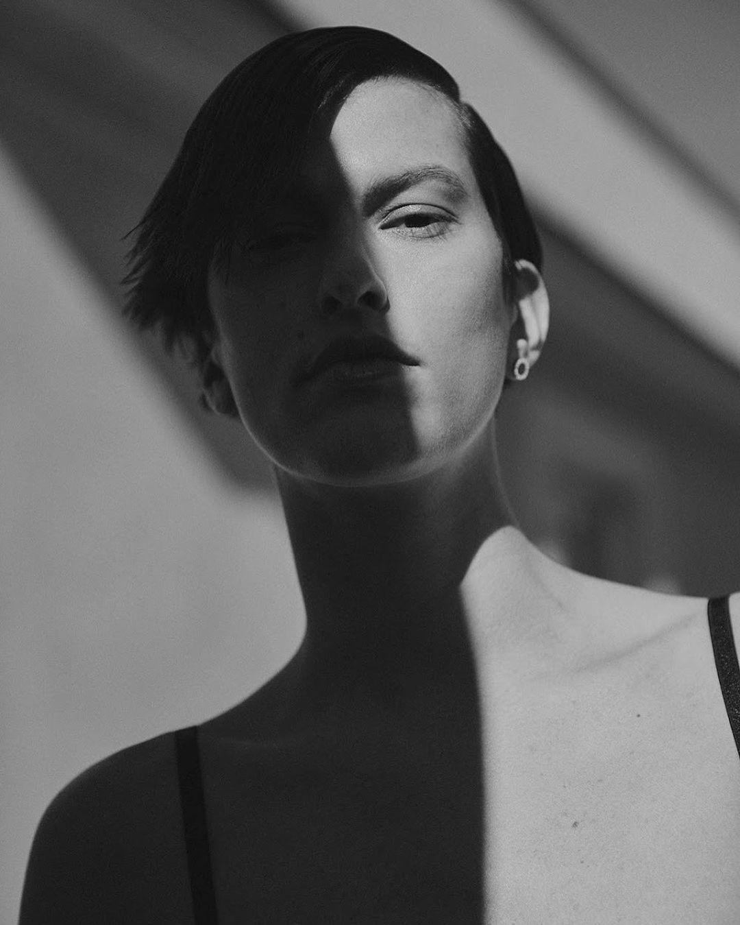Close-up monochrome portrait of a short-haired woman with strong shadows cutting across her face by Stefano Galuzzi.