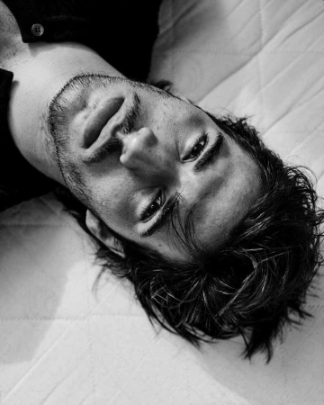 Close-up monochrome portrait of a man lying down looking upward, photographed by Stefano Galuzzi.