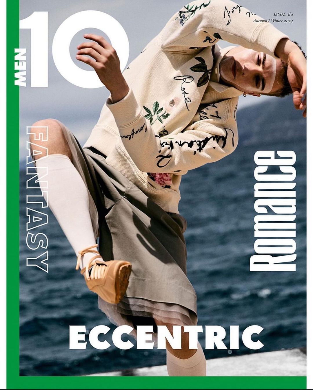 Magazine cover featuring a person in a hoodie and shorts posing outdoors with ocean background and the text "10 Men Fantasy Romance Eccentric".