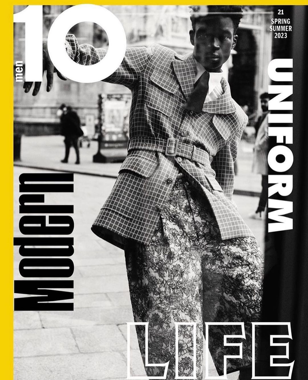 Ten Men magazine cover featuring a model in a checkered coat and patterned pants, posing in an urban setting, with bold typography.