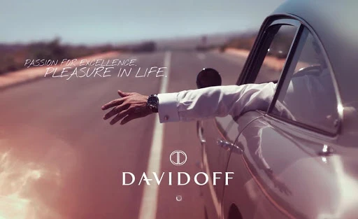 Car commercial featuring an arm extended out of the driver's side window on an open road with the DAVIDOFF logo and slogan visible.